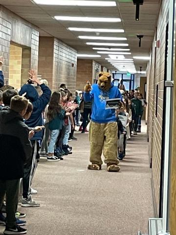 Students and mascot parading down hall.